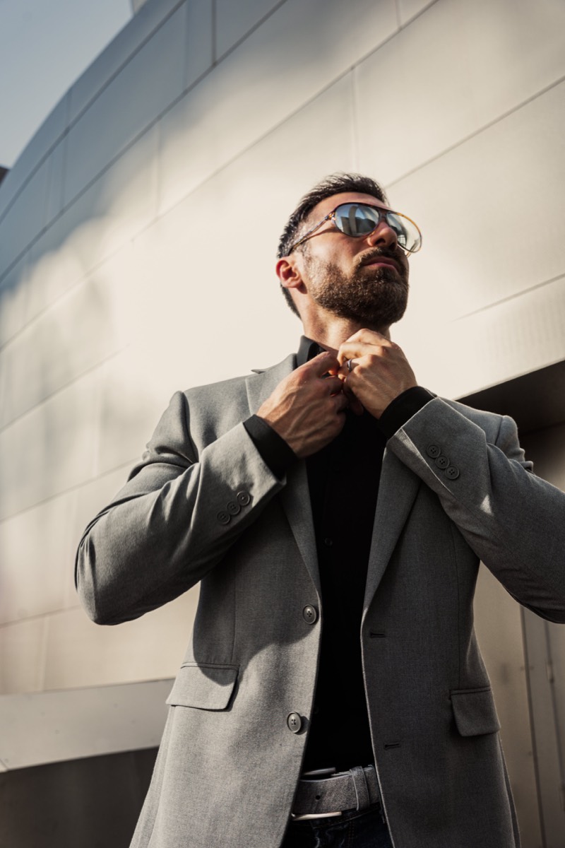 Clear-framed Remo Tulliani sunglasses being lowered by a man in a teal jacket